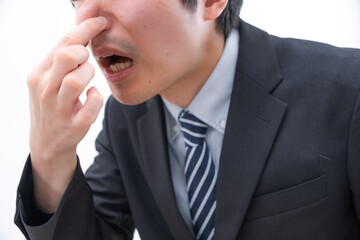鼻を摘んで臭さに耐える男性