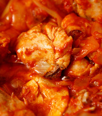 A bowl of red sauce with meat in it