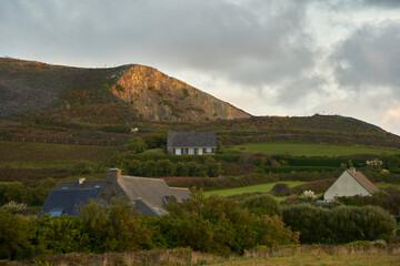 Sunrise Over Rolling Hills and Breton Houses in Normandy: Morning Serenity with Rocky Terrain.