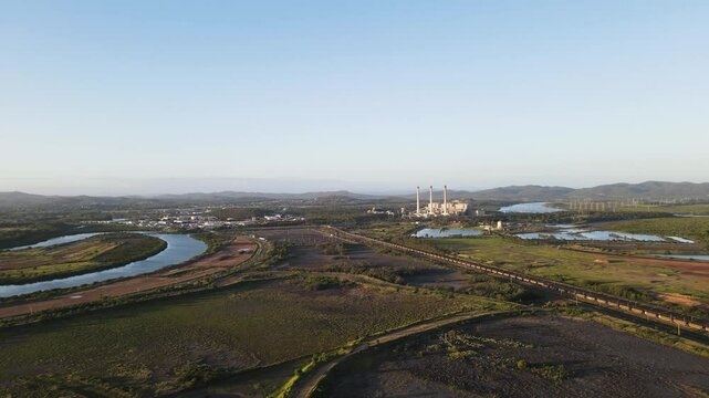 Industrial landscape scene with a rail line running through a conservation wetland area to a power station. Drone view