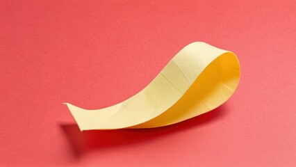 a vibrant yellow paper strip elegantly curves against a bold red background