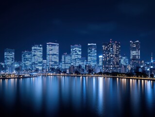 Obraz premium Nighttime city skyline with illuminated skyscrapers reflecting on calm water