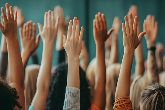 Diverse group of people raising their hands in unison, symbolizing engagement, participation, and collective decision-making in a collaborative environment, selective focus