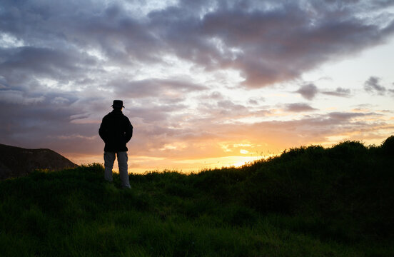Man in silhouette watching sunset at Cape Brett Peninsula. Bay of Islands. New Zealand.