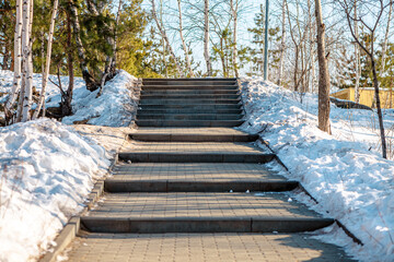 Concrete block paved path bordered by a metal fence and snow going slightly uphill towards a...