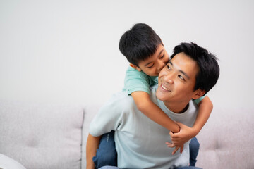 Fototapeta premium Portrait of boy on father's back, embrass him with love and smile. Happy and kind dad together at living room. Relationship, bonding in family with white background.