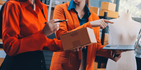 Fashion blogger concept, Young Asian women selling clothes on video streaming.Startup small business SME, using smartphone or tablet taking receive and checking in office.