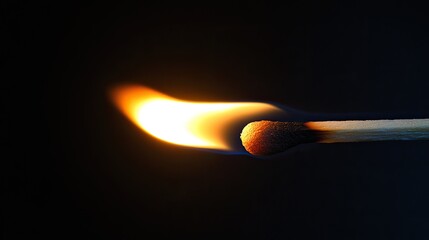 A burning matchstick with a small, glowing flame, casting a soft, focused light against a dark background.