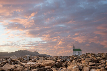 small cute white wooden chapel in a barren volcanic landscape. Sunrise, landscape shot of Ermita...