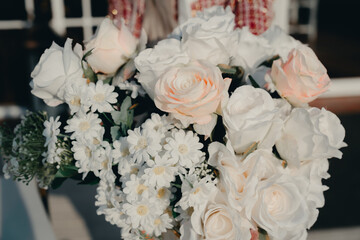 Beautiful bouquet of white and pastel flowers held by a person dressed elegantly against a blurred outdoor background