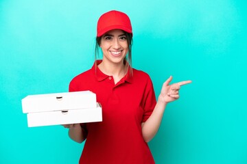Pizza delivery woman with work uniform picking up pizza boxes isolated on blue background pointing...
