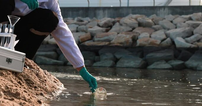 Two Ecologists in chemical PPE suits to check samples of water and collect samples for examination of water pollution. Two Ecologists Examining Polluted Water in Polluted Area