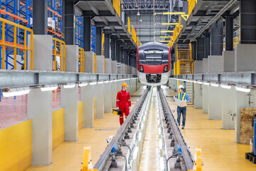 Electric train technician engineer with blueprints checking controls system for security functions...