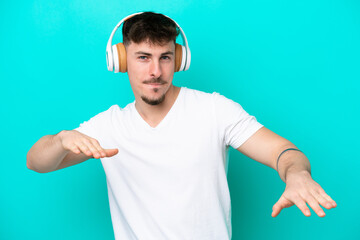 Naklejka premium Young caucasian handsome man isolated on blue background listening music and dancing