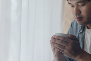 A young man is drinking a cup of coffee.