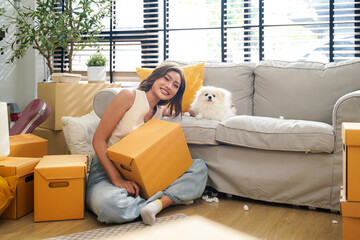 Young women with dog moving home while packing boxes together and happy in new home.  Asia women...