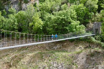Fototapeta premium Mother and son crossing a suspension bridge on a hiking route in Congost Mont Rebei
