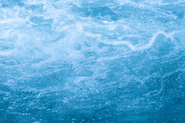 Blue water with ripples on the surface. Defocus blurred transparent blue colored clear calm water surface texture with splashes and bubbles. Water waves with shining pattern texture background.