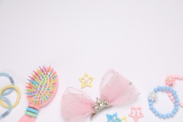 Different hair accessories and brush on light background, flat lay. Space for text