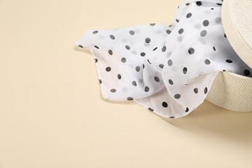 Dotted scarf in box on beige background, closeup. Space for text