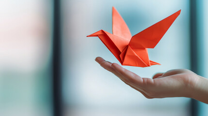 Hand Releasing an Origami Bird Into the Air with a Soft Background Setting