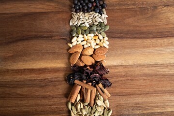 A vibrant display of various seeds and spices arranged on a wooden surface, showcasing their natural colors and textures.