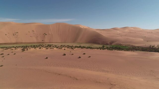 The quadcopter flies in front and takes off the dune with its eyes and the river that flows under it, then flies up and opens the whole view of the Gobbi desert in Mongolia.