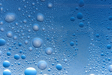 Water droplets cluster on a blue surface, creating a captivating abstract pattern that highlights the beauty of nature and moisture.