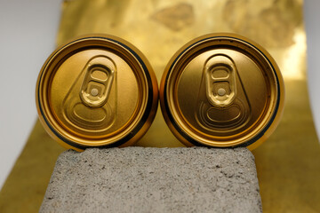 Full or unopened aluminum cans. Two golden aluminum cans on the rough concrete surface....