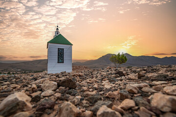 small cute white wooden chapel in a barren volcanic landscape. Sunrise, landscape shot of Ermita...