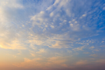 The morning sky with soft scattered clouds. The sky has a gradient from warm pale yellow below to cool light blue above. Cloud formations are soft and thin.