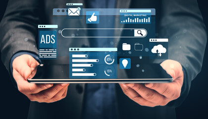 Digital marketing concept with businessperson holding a tablet displaying floating online advertising icons, analytics, and social media symbols.