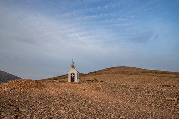 small cute white wooden chapel in a barren volcanic landscape. Sunrise, landscape shot of Ermita...