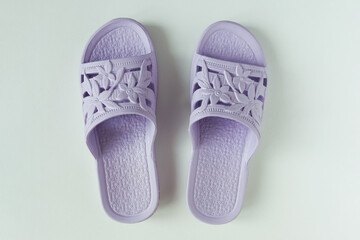 Purple rubber flip flops with floral pattern. White background.