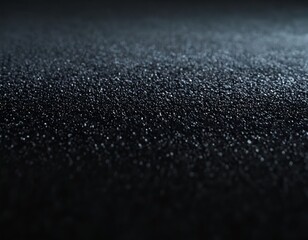 Close-up view of textured black surface with shimmering particles reflecting light.