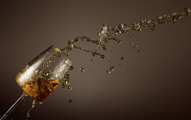 Glass and white wine splash on a beige background.