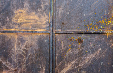A weathered, rusted blue metal door with gold streaks and scratches.