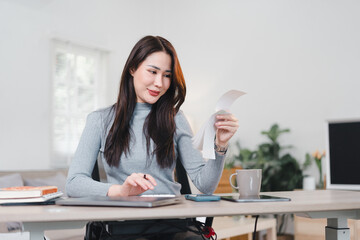 Stressed Asian businesswoman sitting at desk, holding document, surrounded by phone, coffee mug,...