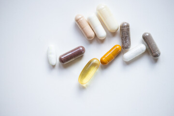 taking pills and supplements capsules on white background