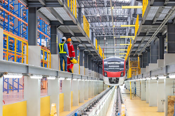 Electric train technician engineer with blueprints checking controls system for security functions...