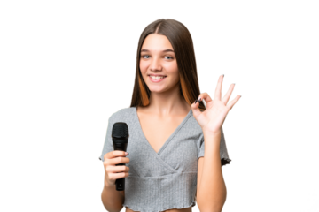 Teenager singer girl picking up a microphone over isolated background showing ok sign with fingers