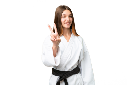 Teenager girl doing karate over isolated chroma key background smiling and showing victory sign