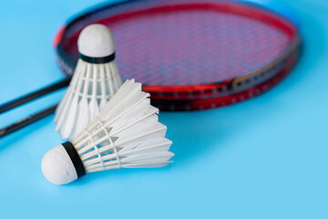 Badminton sport equipments, racket and white cream shuttlecock feather ball on blue floor, soft and selective focus.