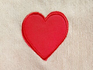 Red heart shape wool on beige Corduroy fabric texture. Valentine's day concept background.