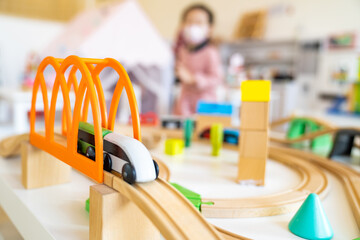 Green white wooden train toy crossing the bridge on river. Close up of wooden toy railway with...