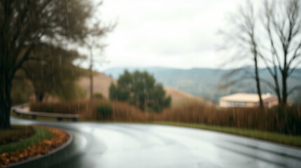 Fototapeta premium Blurred background of a wet road with trees and distant hills in the rain, creating a moody and atmospheric scene.