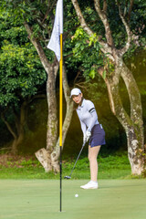 Asian woman professional golfer play golf at golf course with green golf course background, Asian woman golf player swing tee off on the green, Healthy and Lifestyle.