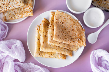 Delicious breakfast: thin large pancakes on a white plate on a pink background. Thin pancakes for dessert . View from above. Close-up
