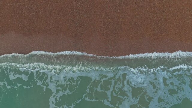 Aerial top view of the sea reaching a sandy coast in the UK