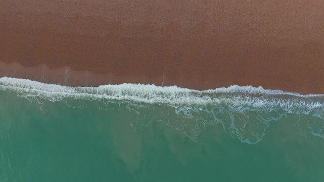 Aerial top view of the sea reaching a sandy coast in the UK